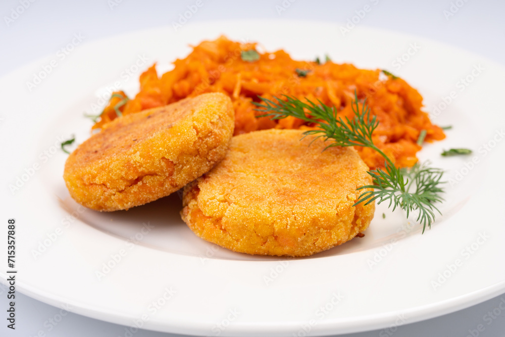 Vegetarian Lunch. Carrot cutlets with stewed cabbage on a white plate and a white background Vegetarian Lunch. Carrot cutlets with stewed cabbage on a white plate and a white background
