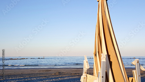 beautiful sunrise with sun reflection on cesenatio riccione rimini beach with open umbrellas