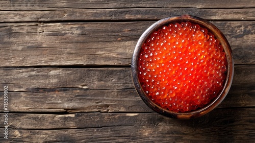 Red caviar in a plate on a wooden table, top view. photo