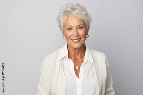Smiling senior woman. Portrait of beautiful senior woman looking at camera and smiling while standing against grey background