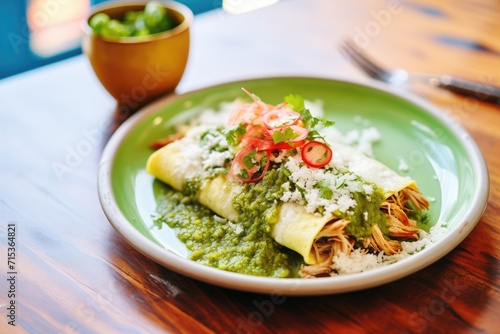 plate of chicken enchiladas topped with green sauce and cheese