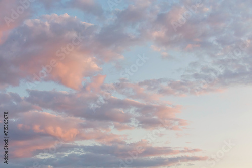 Beautiful fluffy clouds painted in vibrant colors at sunrise. Pink and light blue. Multicolor background or wallpaper