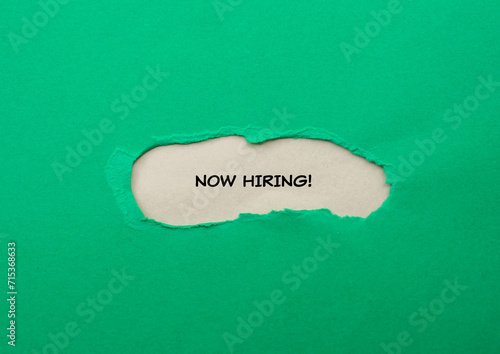 Now hiring lettering on ripped green paper with gray background. Business recruitment concept. Top view, copy space.