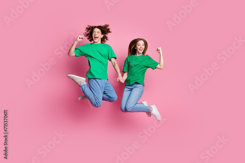 Full length photo of two teenagers girlfriend and boyfriend in relationships jump celebrating anniversary isolated on pink color background