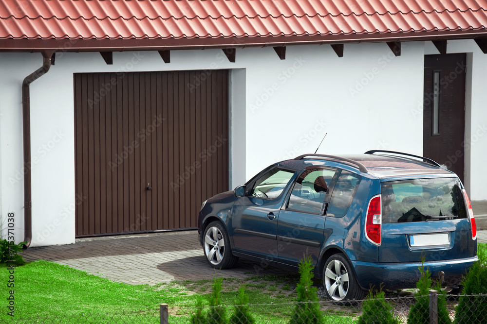 Fototapeta premium blue family car parked near garage of the detached house