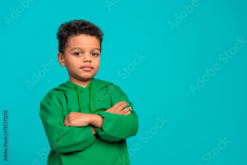 Photo of adorable cute nice boy wear trendy green outfit crossed arms empty space poster isolated on cyan color background