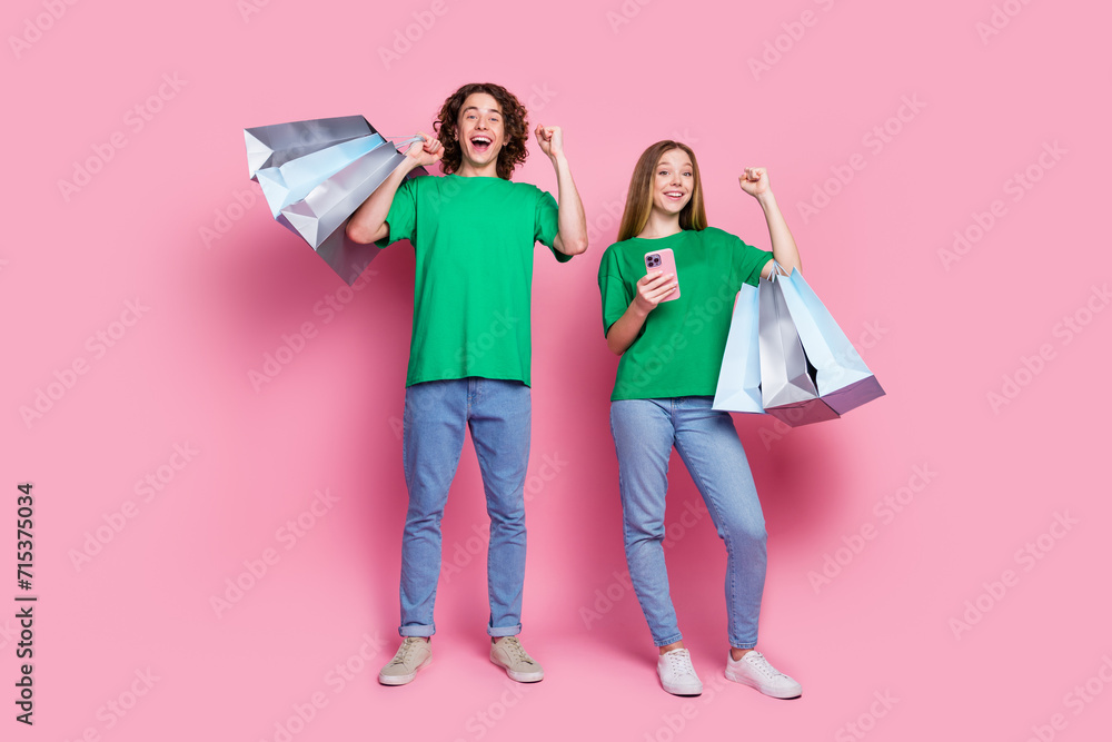 Full body size photo of two overjoyed teenagers raised fists up celebrate big sale aliexpress cheap prices isolated on pink color background Full body size photo of two overjoyed teenagers raised fists up celebrate big sale aliexpress cheap prices isolated on pink color background