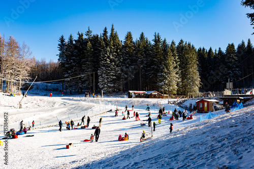 Family winter ski resort Il Lago della Ninfa. Monte Cimone, mountains in the northern Apennines, of Italy, Emilia-Romagna. Slope for children sleighing, snow tubing. People figures, no visible faces. photo