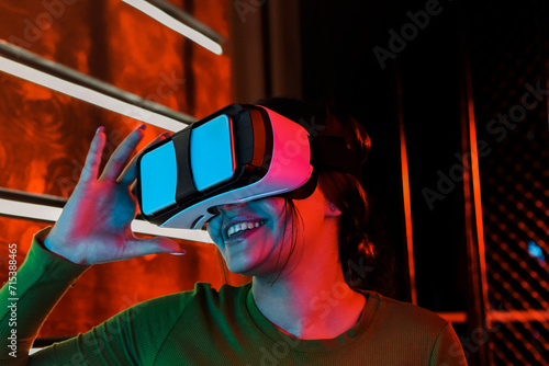 Cheerful woman in VR glasses under neon light