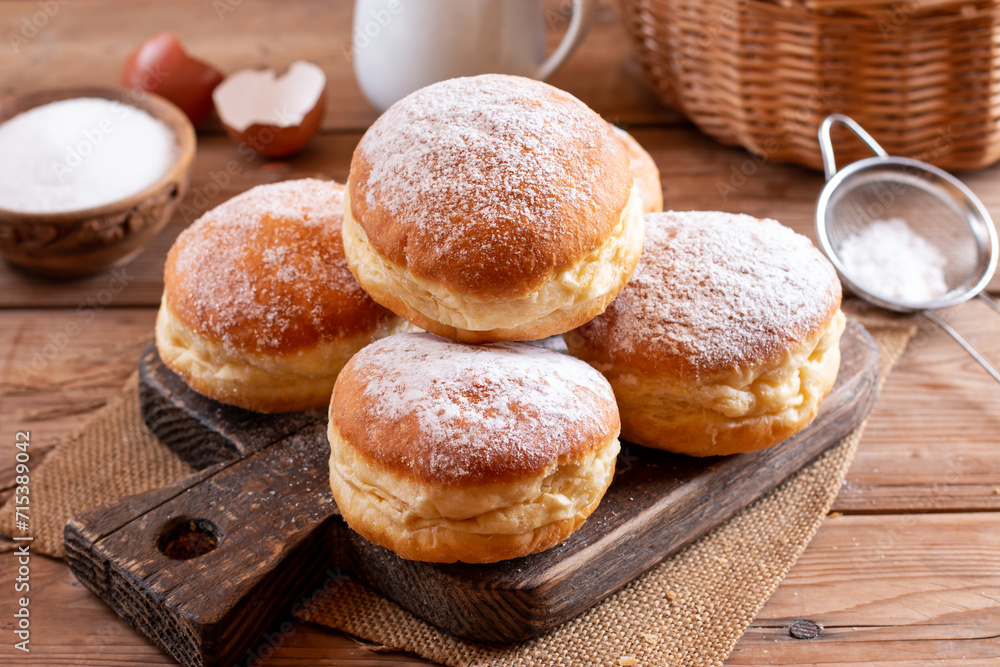 Naklejka premium Hanukkah sweet food doughnuts sufganiyot with powdered sugar and fruit jam on a wooden board. Jewish holiday Hanukkah concept.