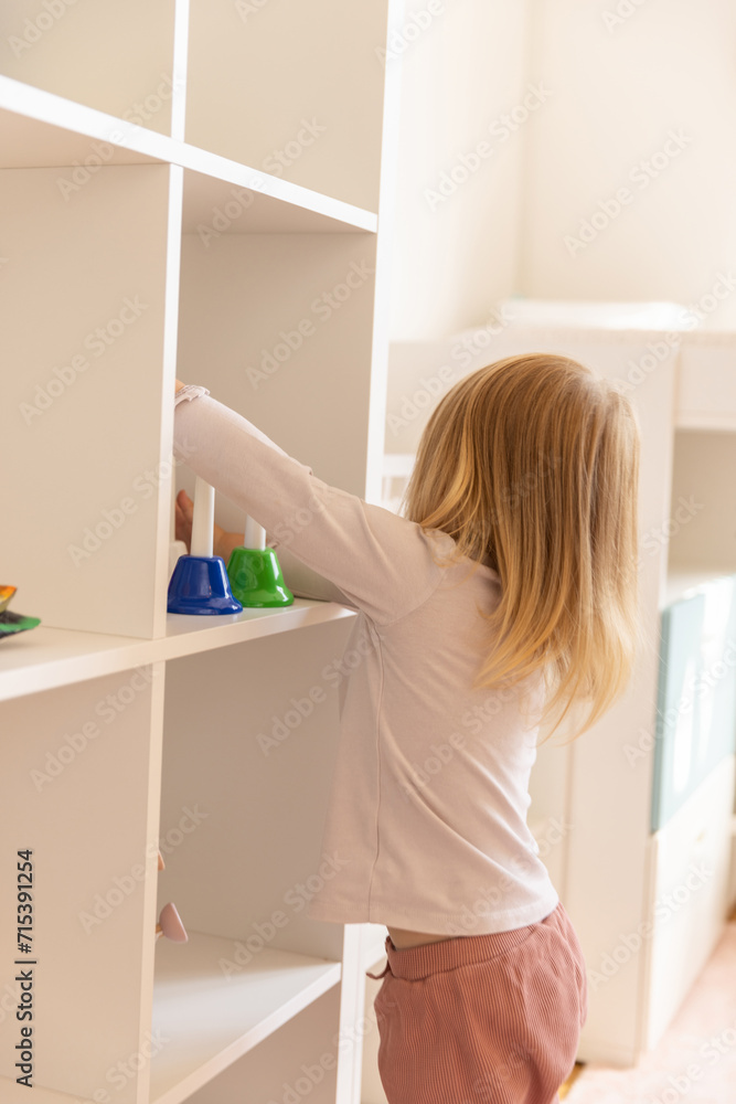 Little girl playing alone in the kindergarten with wooden toys Little girl playing alone in the kindergarten with wooden toys
