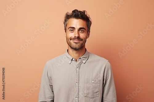 Handsome young man smiling at camera while standing against orange background