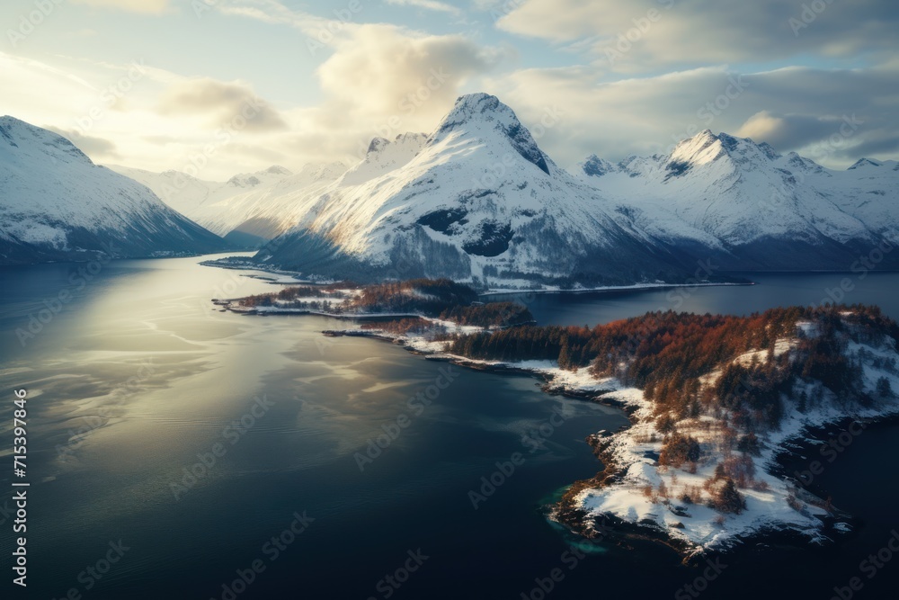  an aerial view of a mountain range with a lake in the foreground and snow covered mountains in the background.