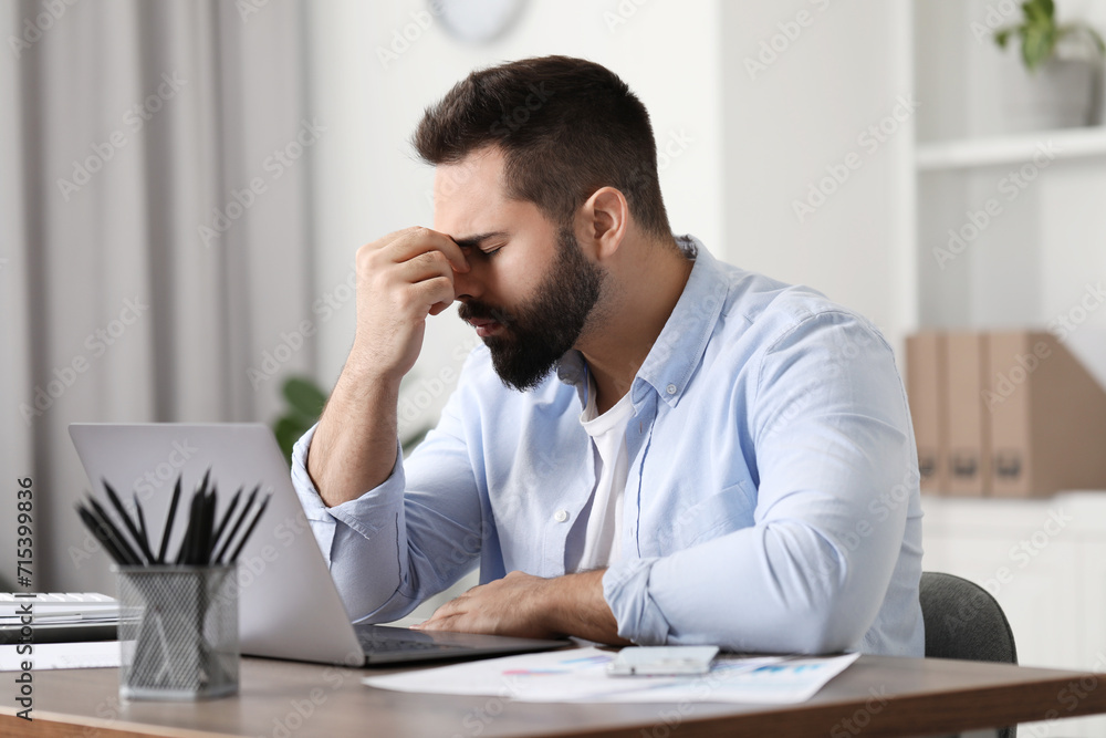 Man suffering from headache at workplace in office Man suffering from headache at workplace in office