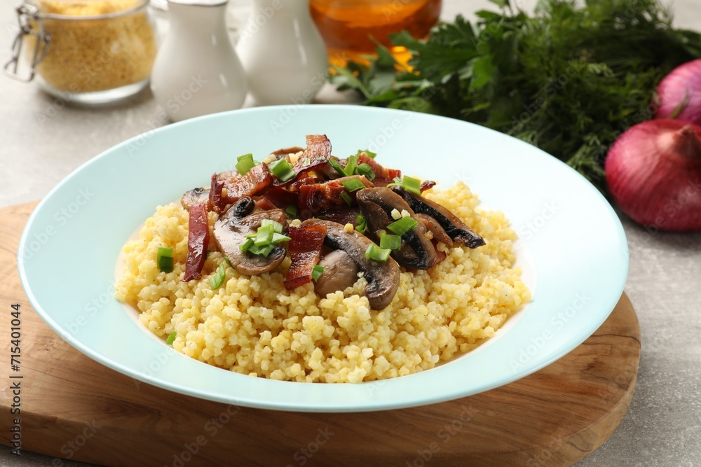 Tasty millet porridge with mushrooms, bacon and green onion on grey table, closeup Tasty millet porridge with mushrooms, bacon and green onion on grey table, closeup