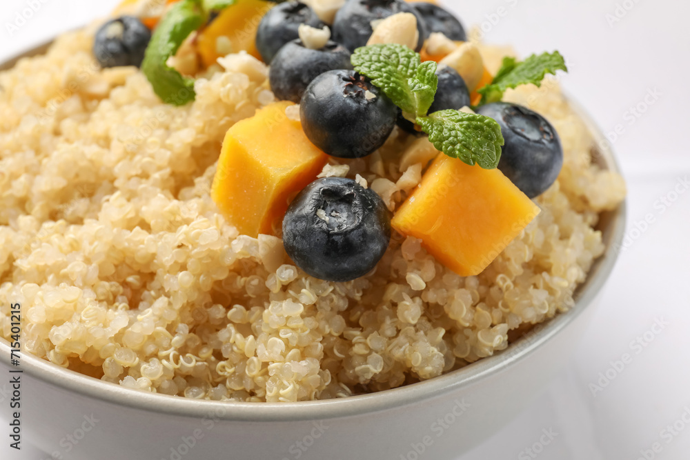 Tasty quinoa porridge with blueberries, pumpkin and mint in bowl on white table, closeup Tasty quinoa porridge with blueberries, pumpkin and mint in bowl on white table, closeup
