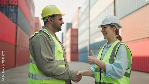 Two industrial engineers man and woman shake hands to celebrate success work together at cargo container yard. Logistic shipping yard business. Teamwork concept