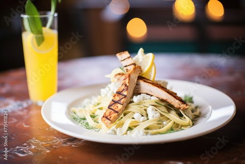 fettuccine alfredo with grilled chicken strips and lemon wedge