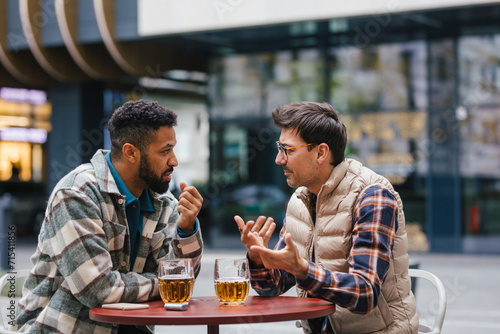 Best friends togehter, drinking beer and talking in bar in city. Concept of male friendship, bromance. photo