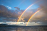 Double rainbow on the horizon between the sea and low clouds. The concept of an unusual natural phenomenon.
