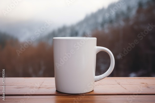  a white coffee cup sitting on top of a wooden table in front of a scenic view of snow covered mountains.