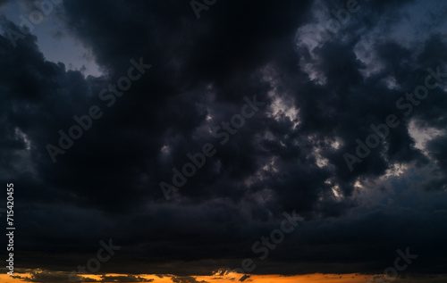 Tropical sunset. Beautiful sunset sky with clouds. Orange sunset, dark clouds in sky. Background of dark clouds before storm. Dramatic clouds. Apocalyptic sky, dark cloud. Overcast sky.