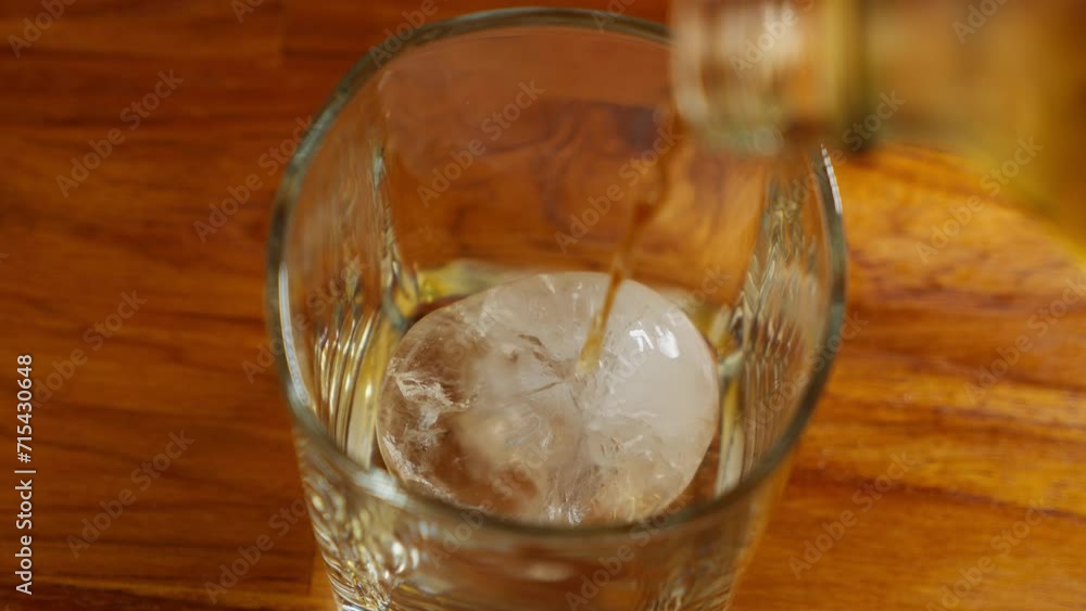 4K Slow Motion Shot of Pouring Whiskey into Glass with Ice Cubes. 4K Slow Motion Shot of Pouring Whiskey into Glass with Ice Cubes.