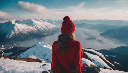 Portrait from the back of the girl traveler in an red sweater and winter hat in the mountains agains 