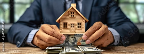 a person in a business suit holding money and making a house model.