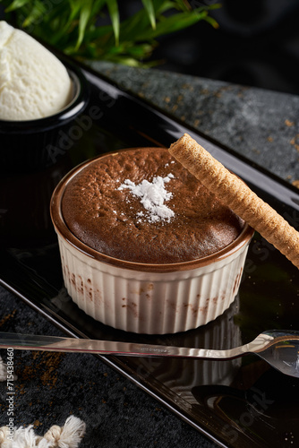 Bild auf Leinwand A close-up photo of a soufflé with biscuits on a black plate