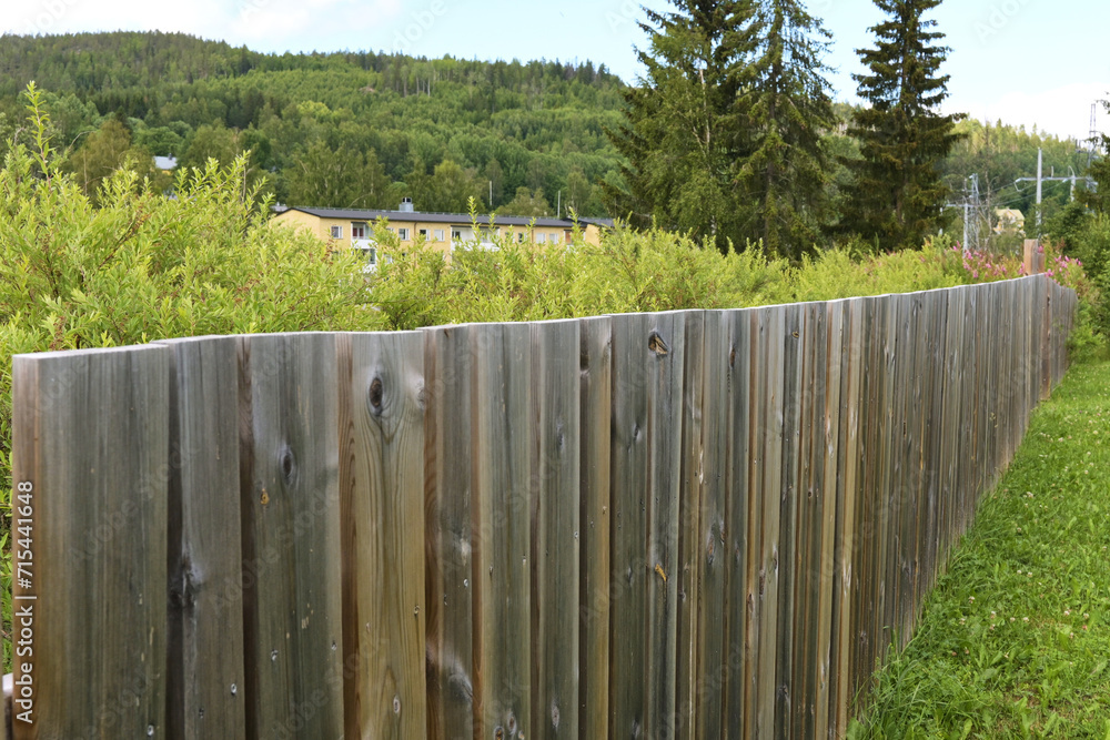 Solid wooden fence in the village in summer.