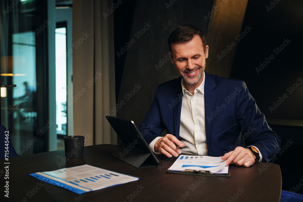 Happy mature businessman analyzing data in conference room Happy mature businessman analyzing data in conference room