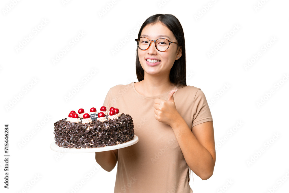 Young Asian woman holding birthday cake over isolated chroma key background giving a thumbs up gesture Young Asian woman holding birthday cake over isolated chroma key background giving a thumbs up gesture