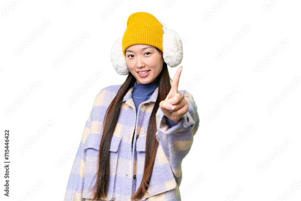 Young Asian woman wearing winter muffs over isolated chroma key background showing and lifting a finger Young Asian woman wearing winter muffs over isolated chroma key background showing and lifting a finger
