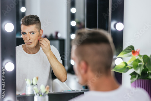 Gay man using mascara to make up in backstage photo