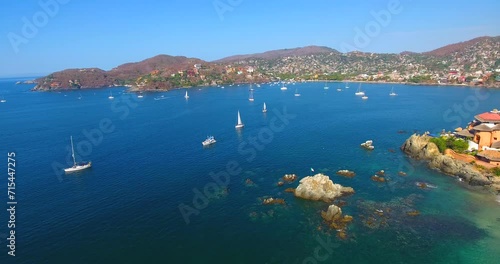 Stationary aerial view of a busy ocean bay filled with sailboats and yachts off the coast of Zihuatanejo, Mexico photo