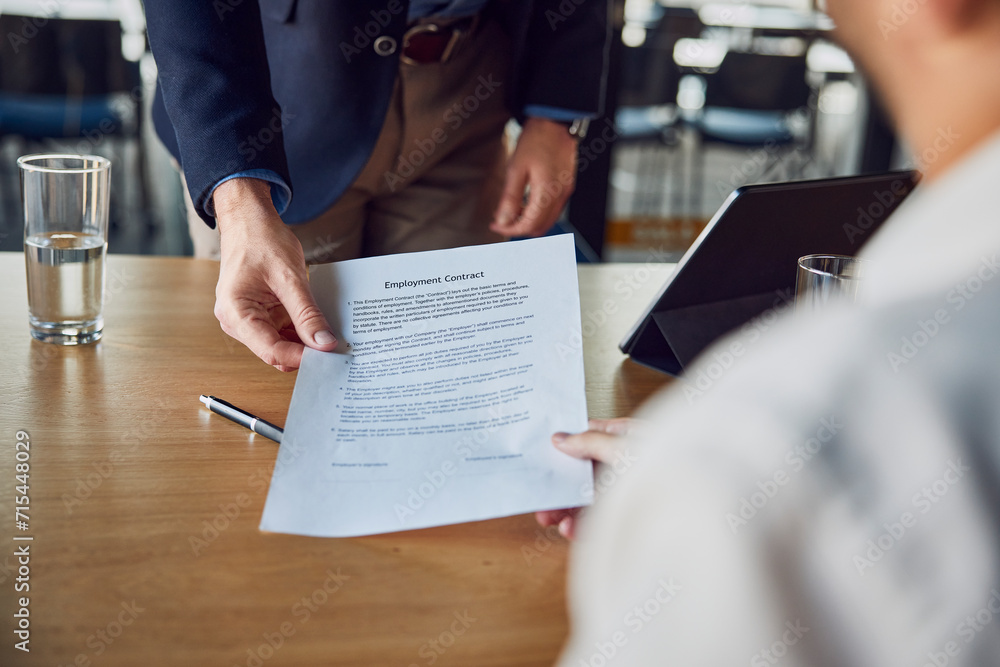 Recruiter giving contract to candidate at desk Recruiter giving contract to candidate at desk