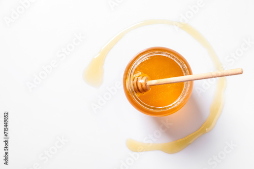 Jar with tasty natural honey and dipper on white background, top view