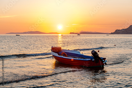 Greece, Ionian Islands, Arillas, Motorboat left on beach at sunset photo