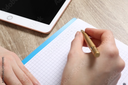 Woman taking notes at wooden table, closeup