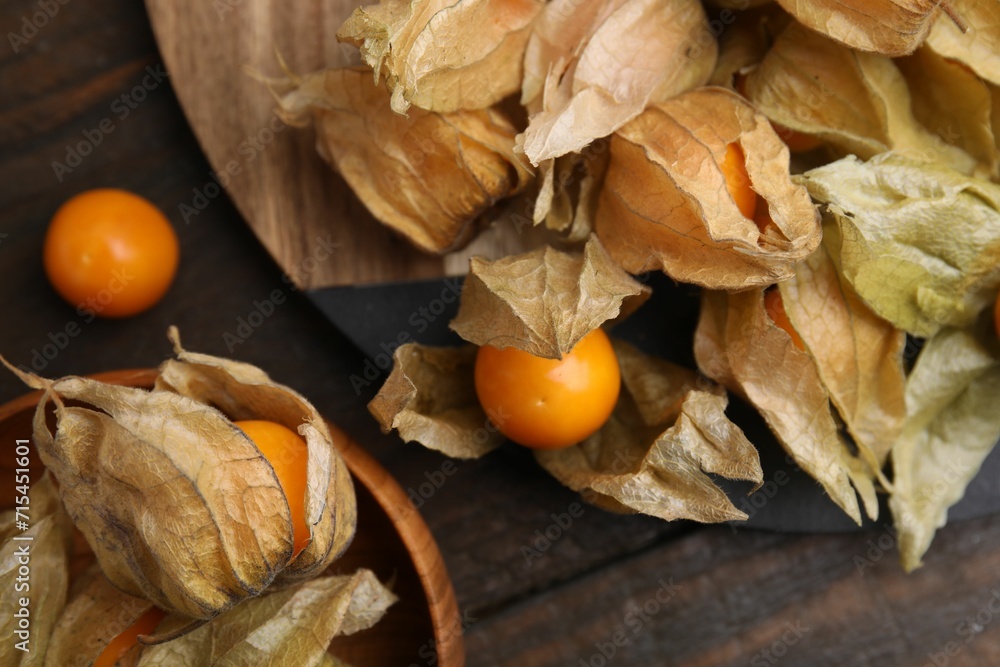 Ripe physalis fruits with calyxes on wooden table, flat lay