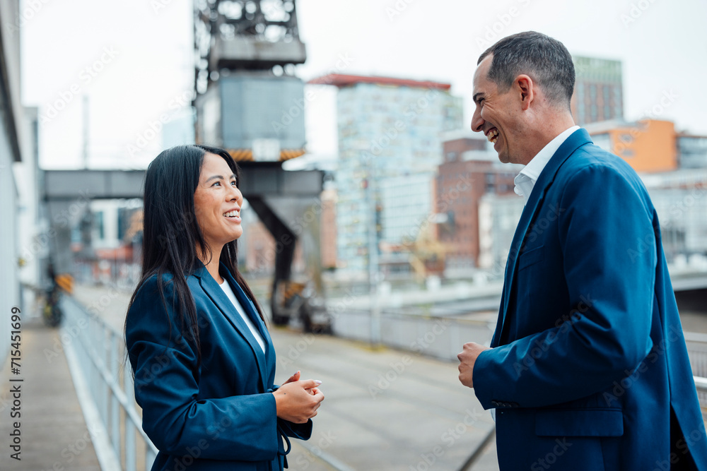 Happy businessman and businesswoman talking in front of buildings Happy businessman and businesswoman talking in front of buildings