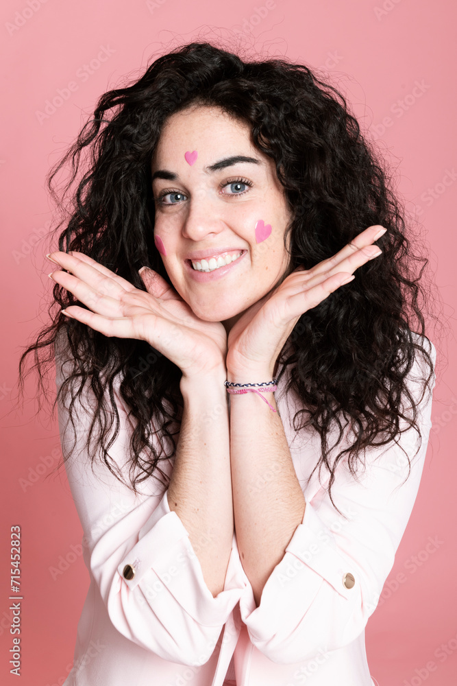 Happy woman with hands on chin and heart shaped stickers over face Happy woman with hands on chin and heart shaped stickers over face