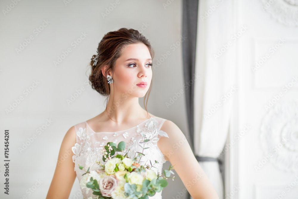 Beautiful brunette woman with bouquet posing in a wedding dress Beautiful brunette woman with bouquet posing in a wedding dress