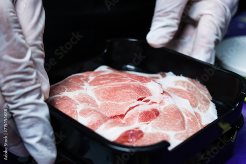 Pork sliced with an automatic meat slicer into round discs, placed in a tray ready to be served with sukiyaki or shabu.