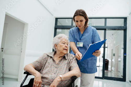 Obraz na płótnie Nurse talking with senior woman, admitting a patient to the hospital, filling documents