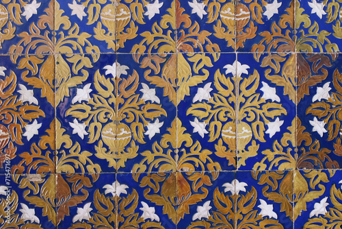Detail of vintage Spanish ceramic tiles.Baroque styled pattern with lilies flowers, vases. Old blue azulejo facade with floral ornaments. Antique building detail. Artistic hand drawn decorative