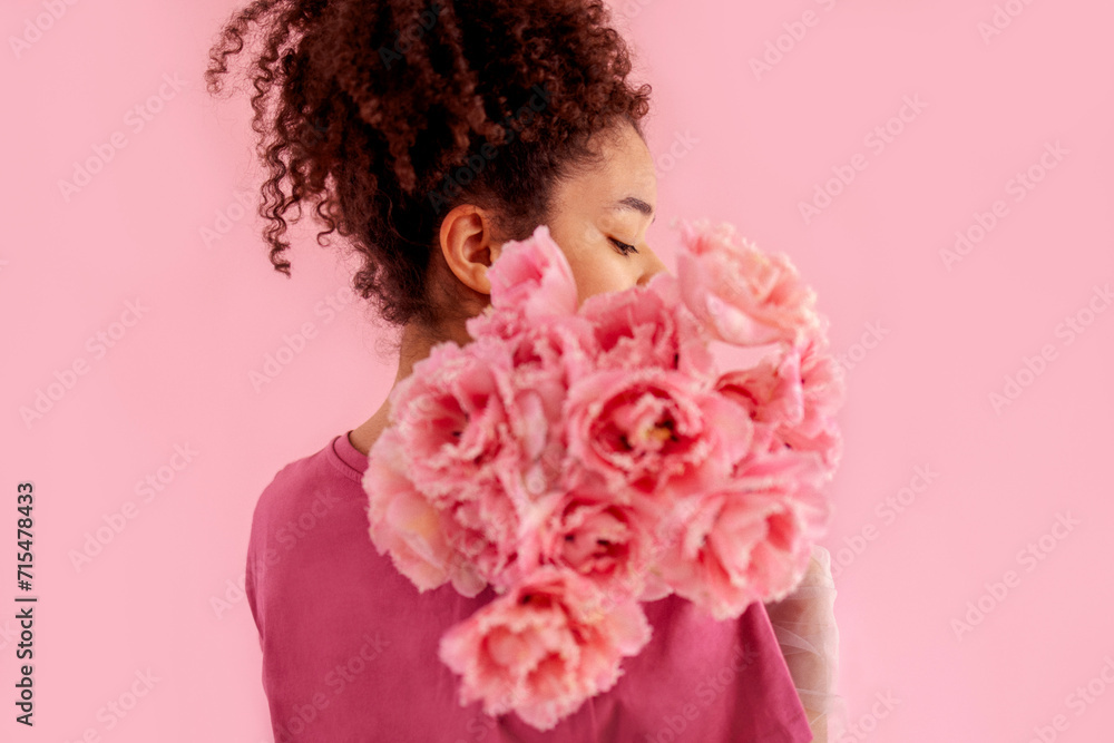 Beautiful african girl holds a bouquet of pink flowers near her face Beautiful african girl holds a bouquet of pink flowers near her face