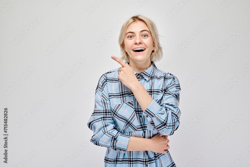 Young blond woman in casual pointing aside finger, demonstrating empty space for product or text isolated on white studio background. Young blond woman in casual pointing aside finger, demonstrating empty space for product or text isolated on white studio background.