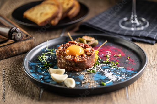 Beef tartare with egg yolk on a plate with garlic and toasted bread